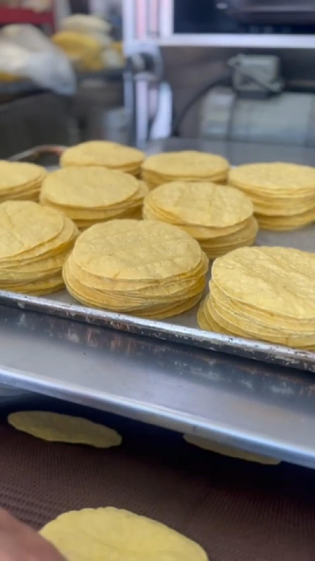 Stacks of organic yellow corn tortillas cooling on a rack, fresh and handmade for California delivery
